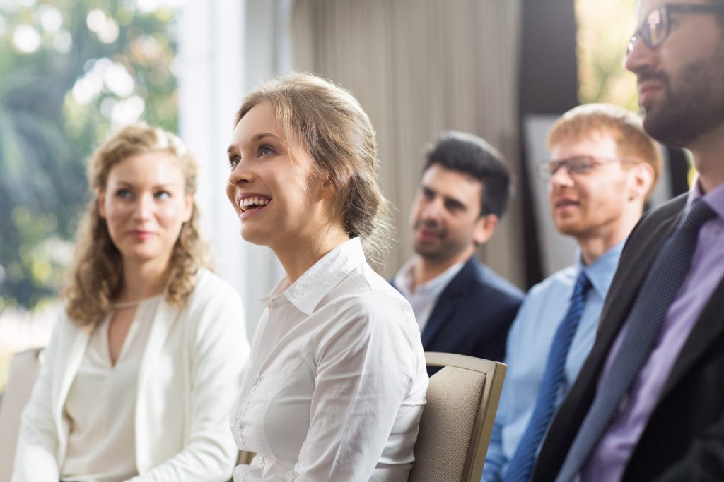 Lachende Teilnehmerin in einem Experten-Vortrag – Zugang zu Speaker:innen und Fachwissen mit Illerhaus Marketing.